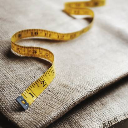 Upholstery workshop. Neutral coloured folded furnishing fabric and a yellow tape measure.